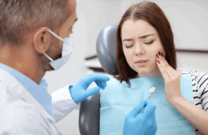 Patient experiencing tooth pain during dental consultation, with dentist examining for TMD treatment options at MA's Family & Cosmetic Dentistry.