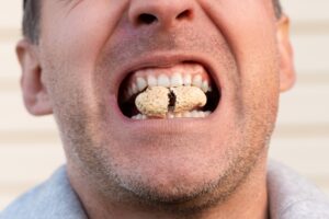 man using teeth as a tool to open peanut